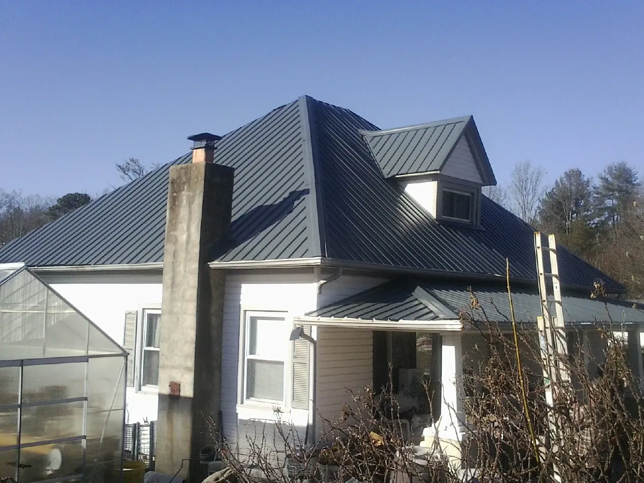 Dark blue standing seam metal roof on a white farmhouse with dormer — Slate & Tile Roof Repair by Roofing Brothers in Turbotville