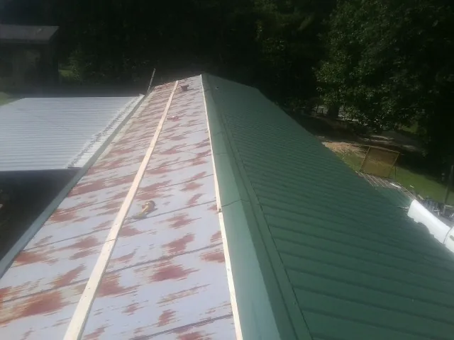 Old rusted panels beside newly installed green metal roofing — Wind Damage Roof Repair by Roofing Brothers in Turbotville