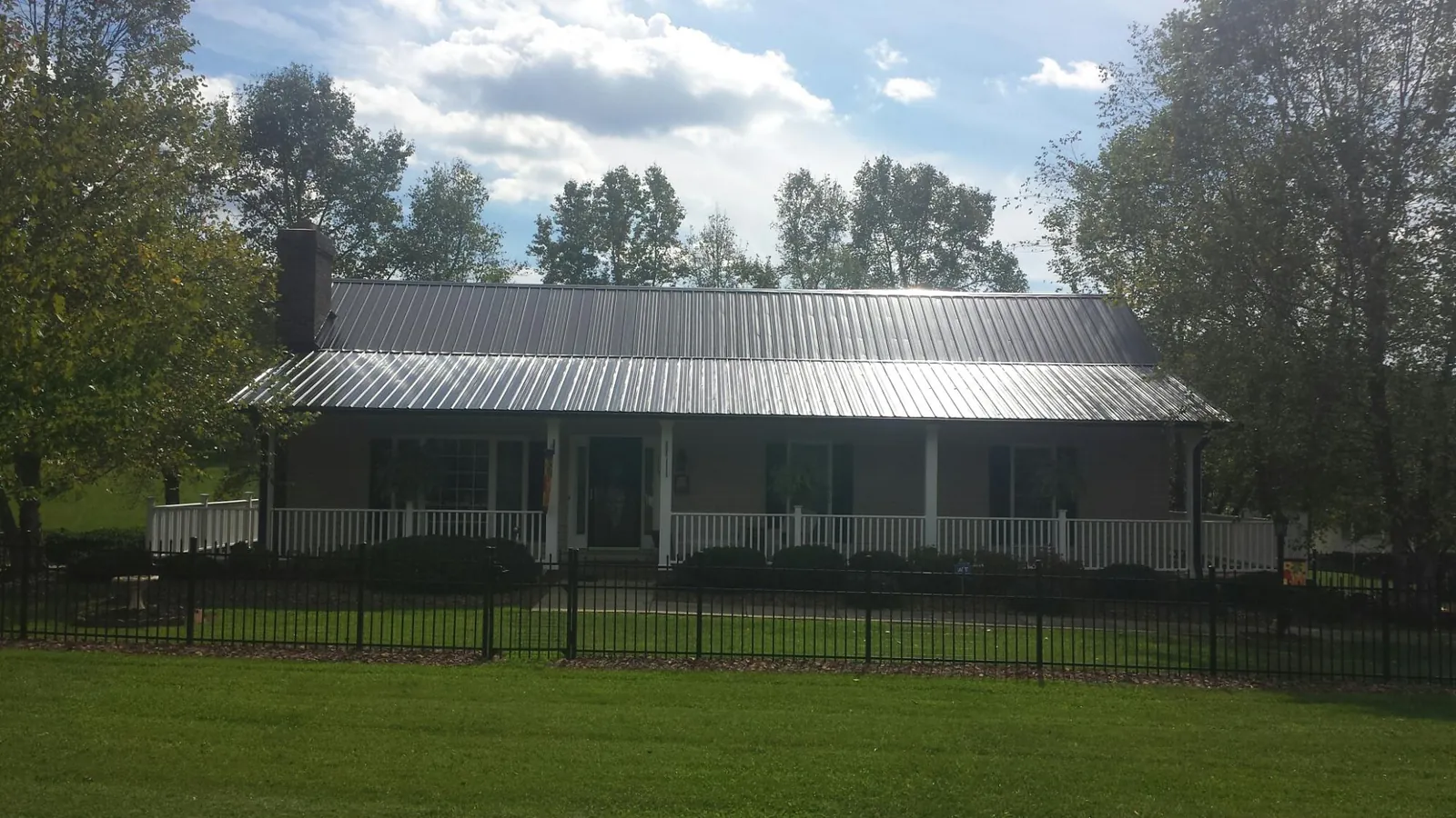 Gray metal roof on a brick ranch with a full width front porch — Gutter Guard Installation work by our crew in Turbotville