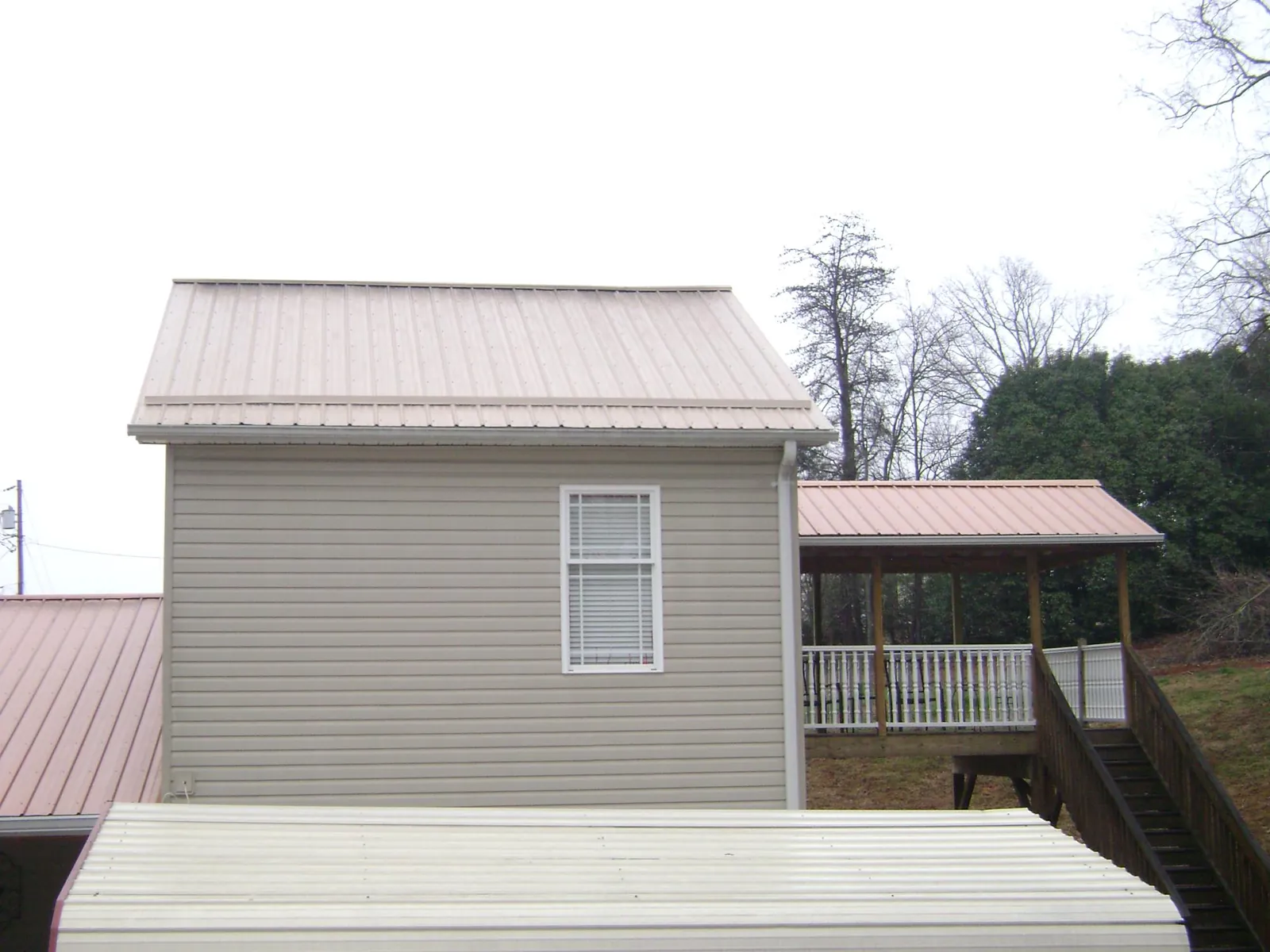 Tan metal roofs on a two story addition and attached porch, from a Roof Replacement job in Turbotville