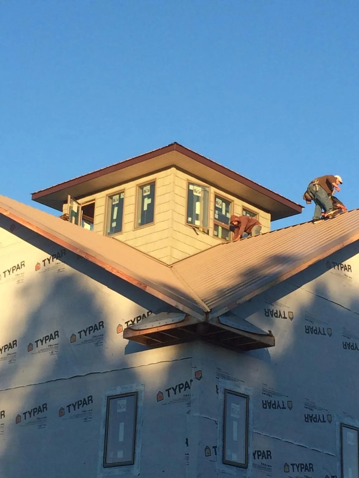 Roofers working around a rooftop cupola on a new metal roof at sunset — Roof Waterproofing in Turbotville by Roofing Brothers